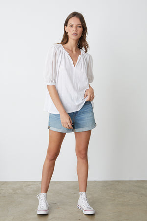 Mallory Top in white with puff sleeves paired with blue denim shorts and white Converse full length front