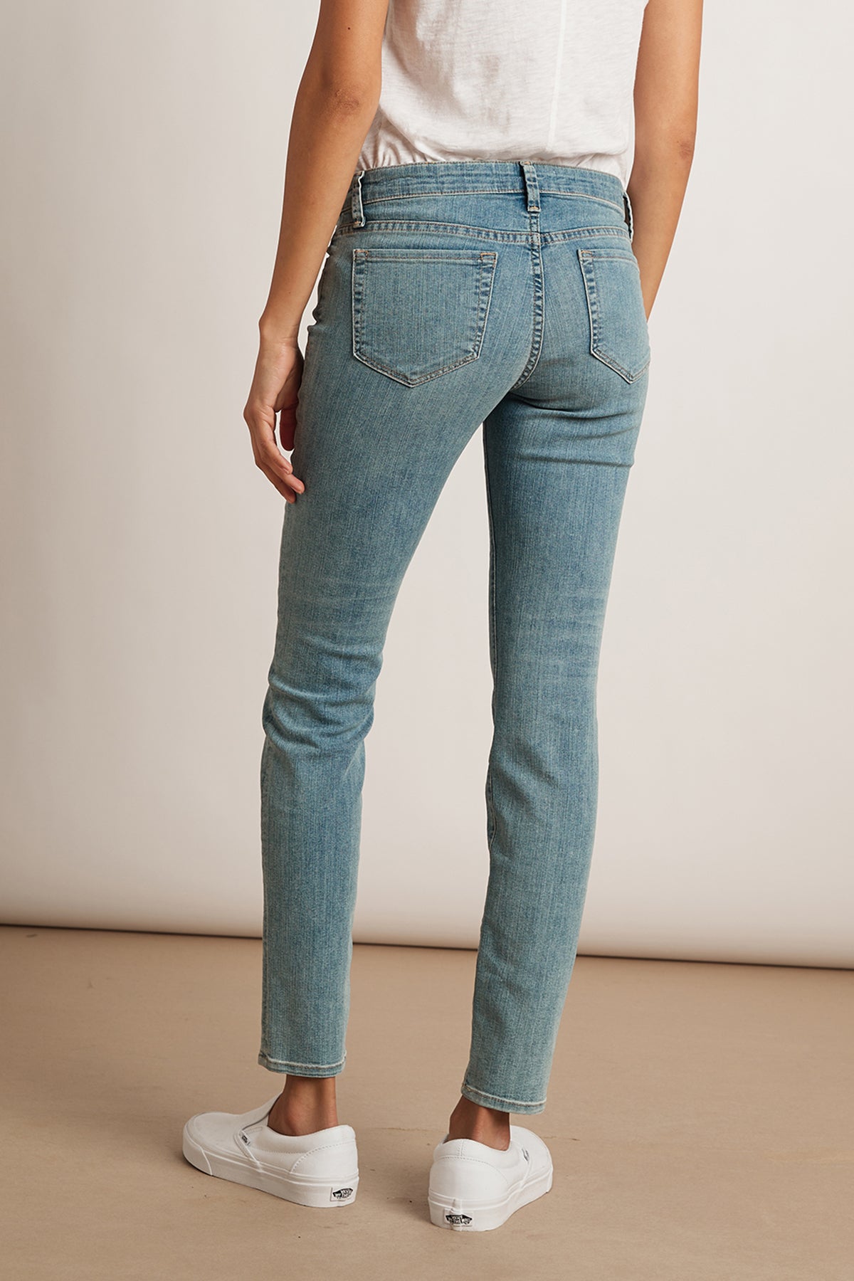The back view of a woman wearing Toni Skinny Jeans, a white t-shirt, and classic denim.-23879001899201