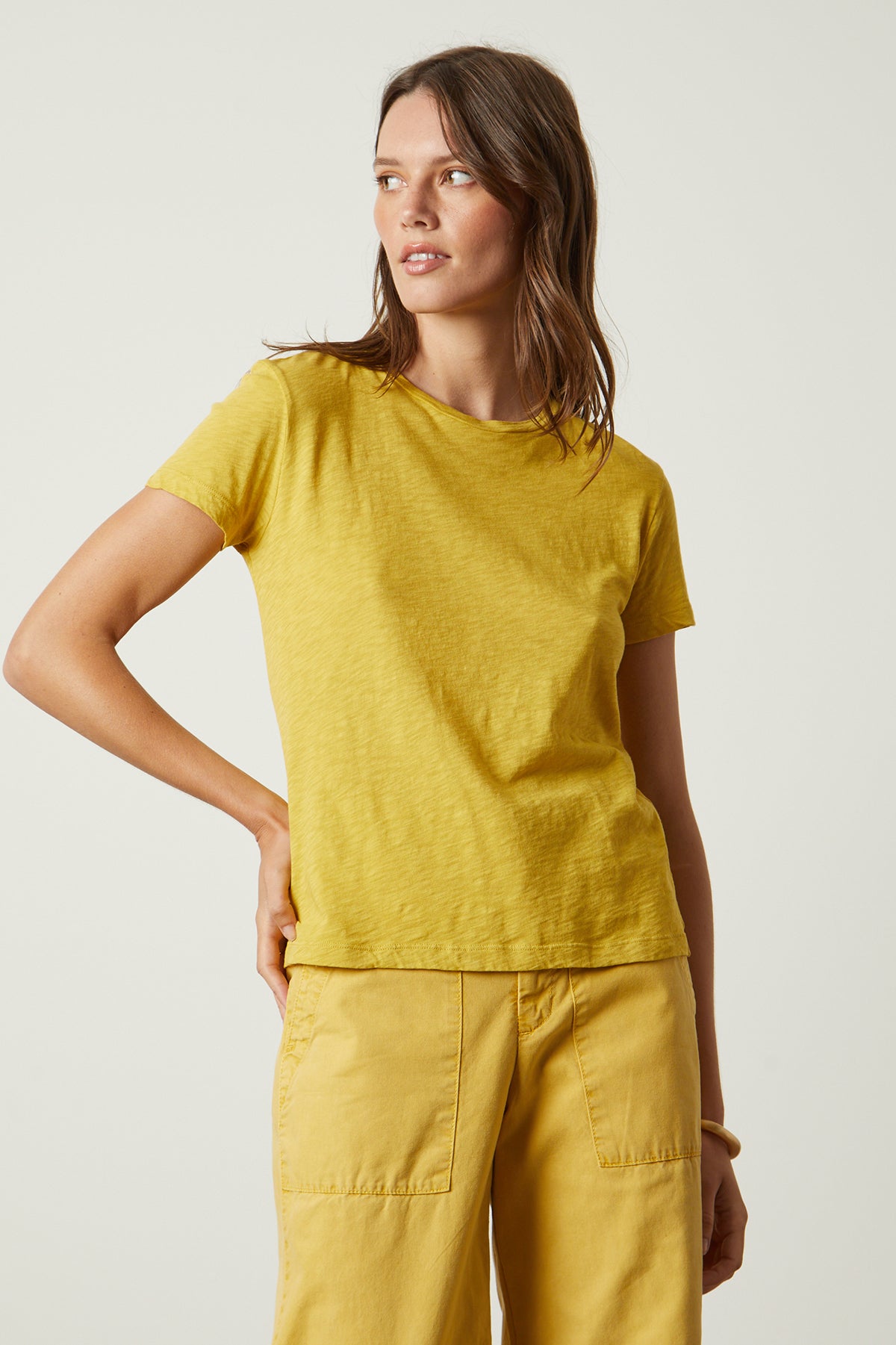 The model is wearing a yellow Velvet by Graham & Spencer SIERRA CREW NECK TEE.-26022866550977