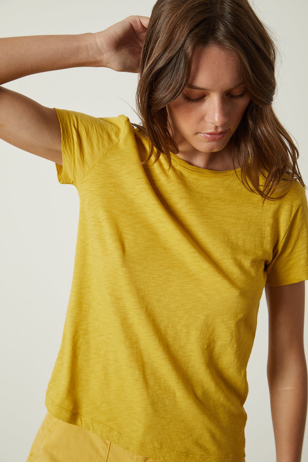   A woman wearing a yellow Velvet by Graham & Spencer Sierra Crew Neck Tee. 