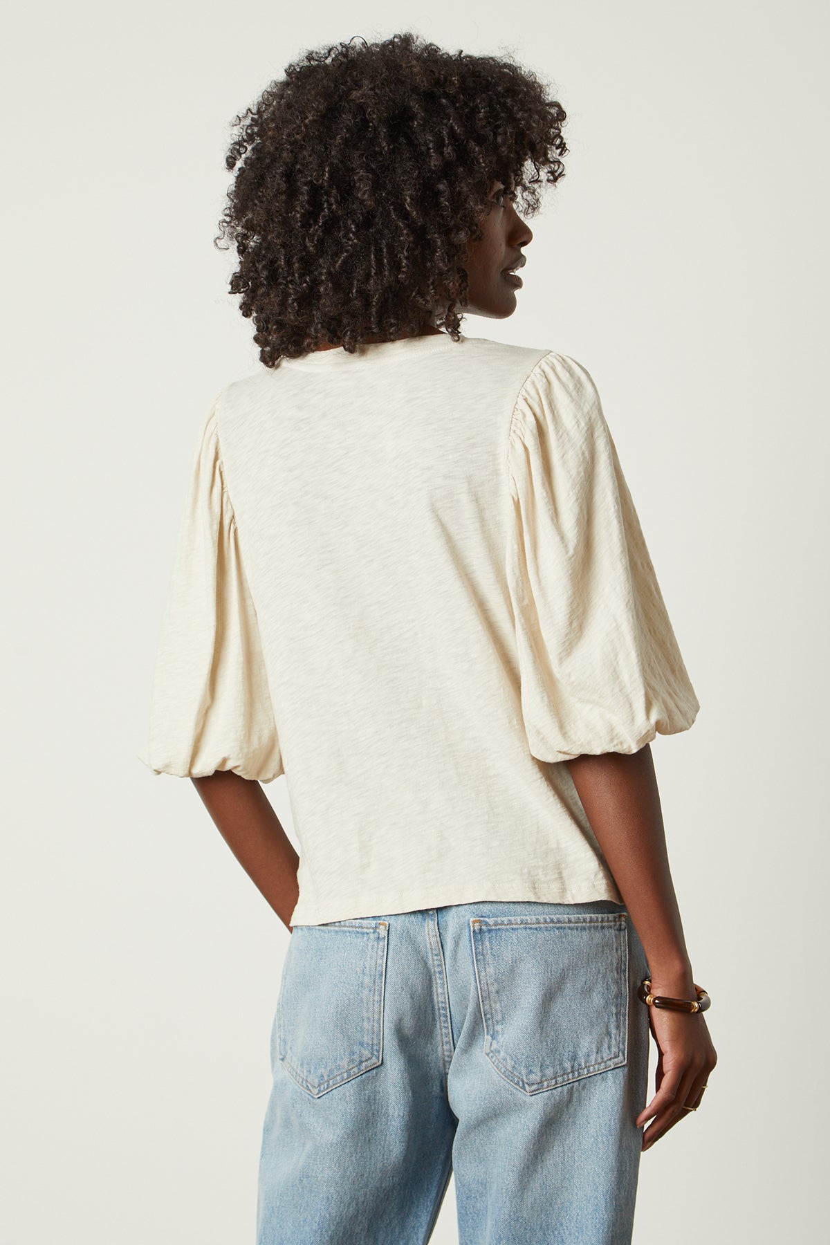 the back view of a woman wearing jeans and a Velvet by Graham & Spencer UMA PUFF SLEEVE TEE.-26022623281345
