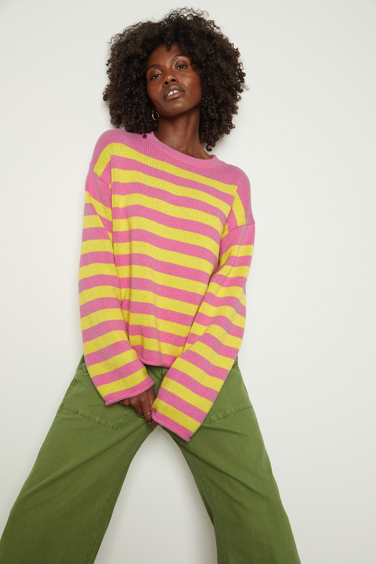   a black woman wearing a Velvet by Graham & Spencer LEX STRIPED CREW NECK SWEATER and green pants. 