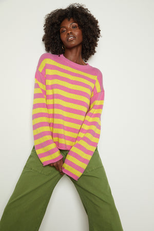 a black woman wearing a Velvet by Graham & Spencer LEX STRIPED CREW NECK SWEATER and green pants.