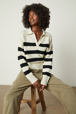 Model sitting on stool wearing Lucie Striped Polo Sweater in Black and Cream and Brylie pant front