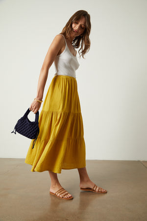 a woman in a yellow midi skirt holding a BENNIE CROCHET BAG by Velvet by Jenny Graham.
