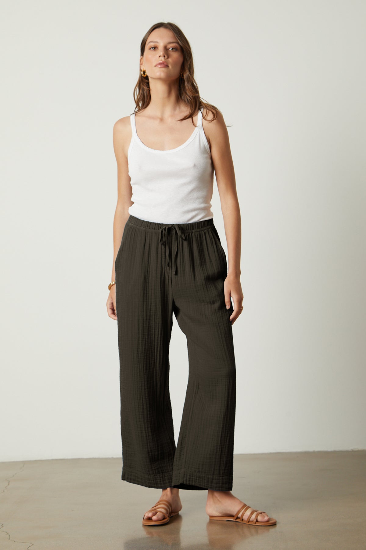 A woman wearing a white tank top and black Velvet by Graham & Spencer FRANNY COTTON GAUZE PANT wide leg pants.-26143109087425