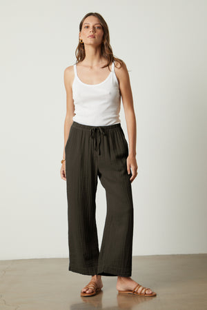 A woman wearing a white tank top and black Velvet by Graham & Spencer FRANNY COTTON GAUZE PANT wide leg pants.