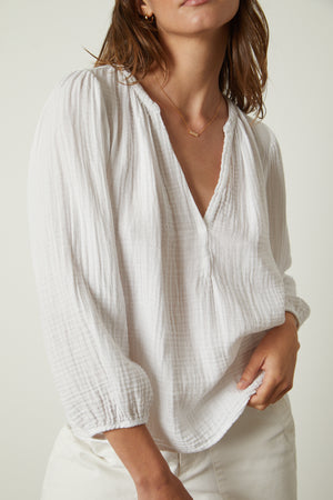 The model is wearing a Velvet by Graham & Spencer MAGGIE COTTON GAUZE V-NECK TOP.