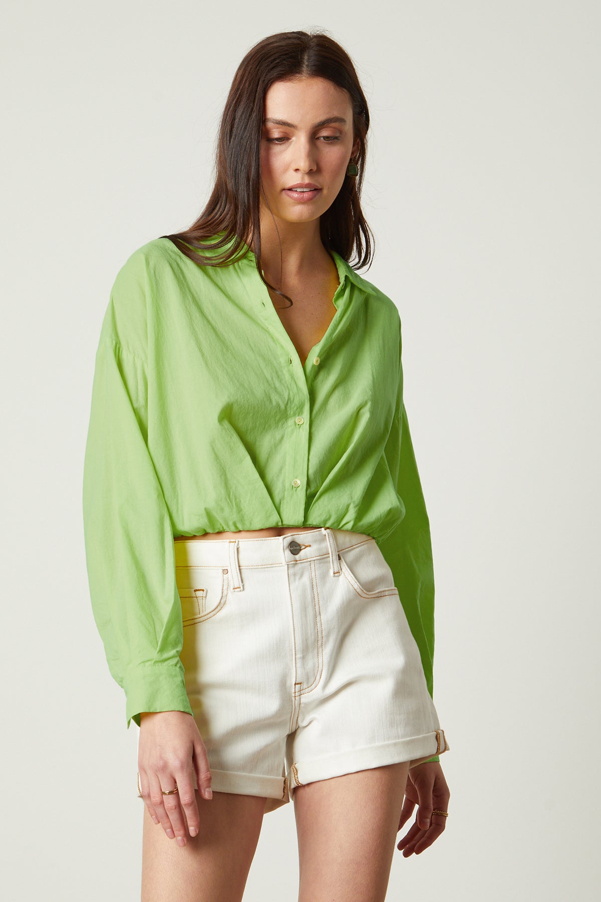   The model is wearing a Velvet by Graham & Spencer JULIA BUTTON-UP CROPPED SHIRT with a lime shirt and elastic hemline. 