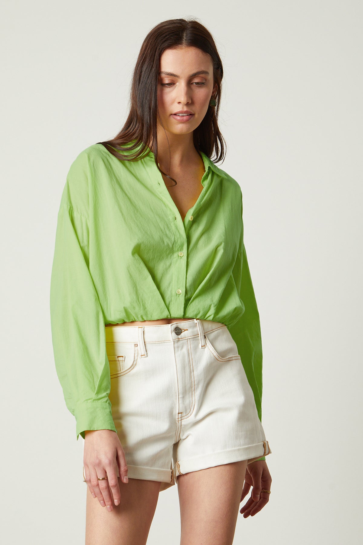 The model is wearing a Velvet by Graham & Spencer JULIA BUTTON-UP CROPPED SHIRT with a lime shirt and elastic hemline.-26215481278657