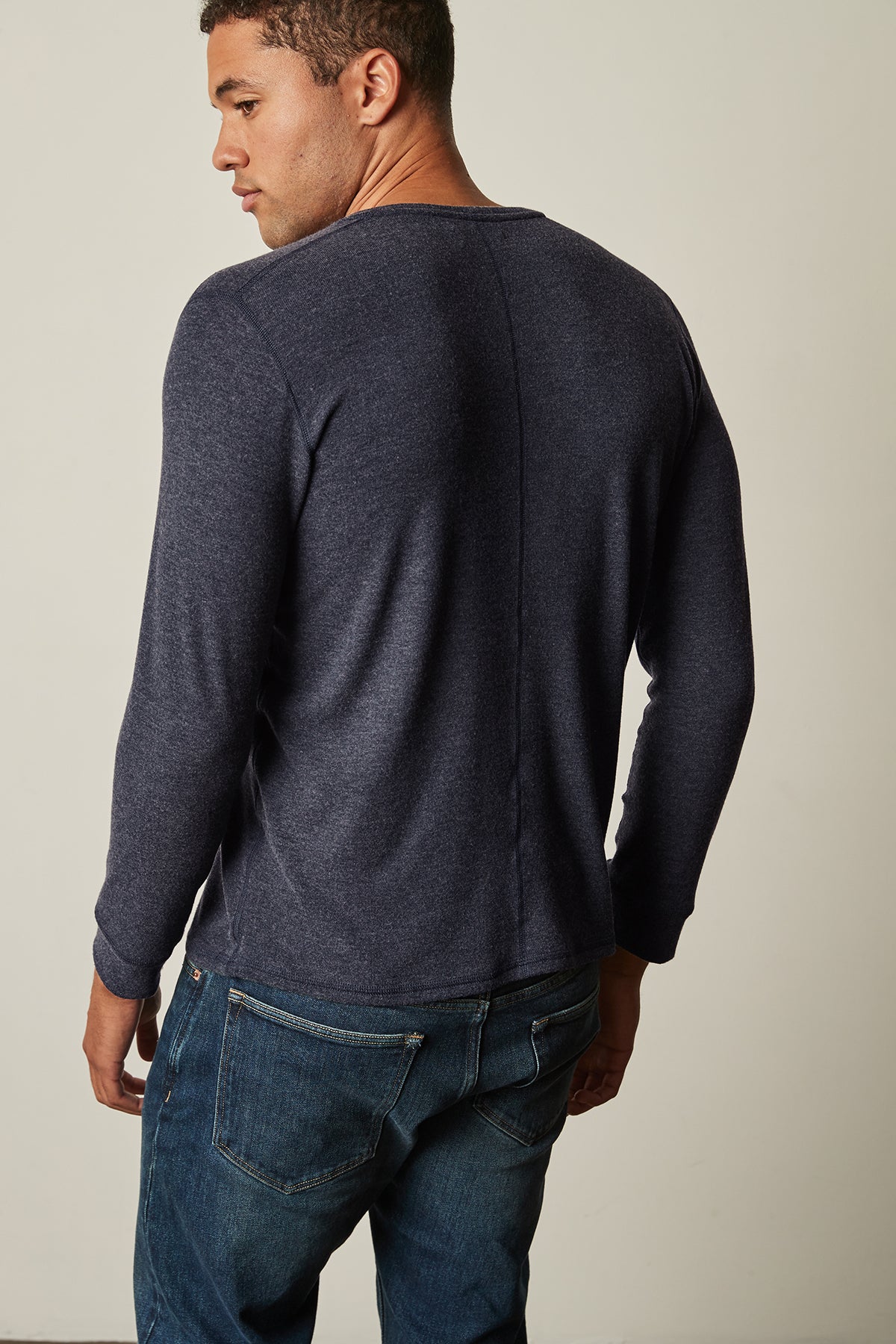 The versatile man is wearing Velvet by Graham & Spencer jeans and a Velvet by Graham & Spencer long-sleeved sweater, showcasing the fabric's layering potential.-25484011765953
