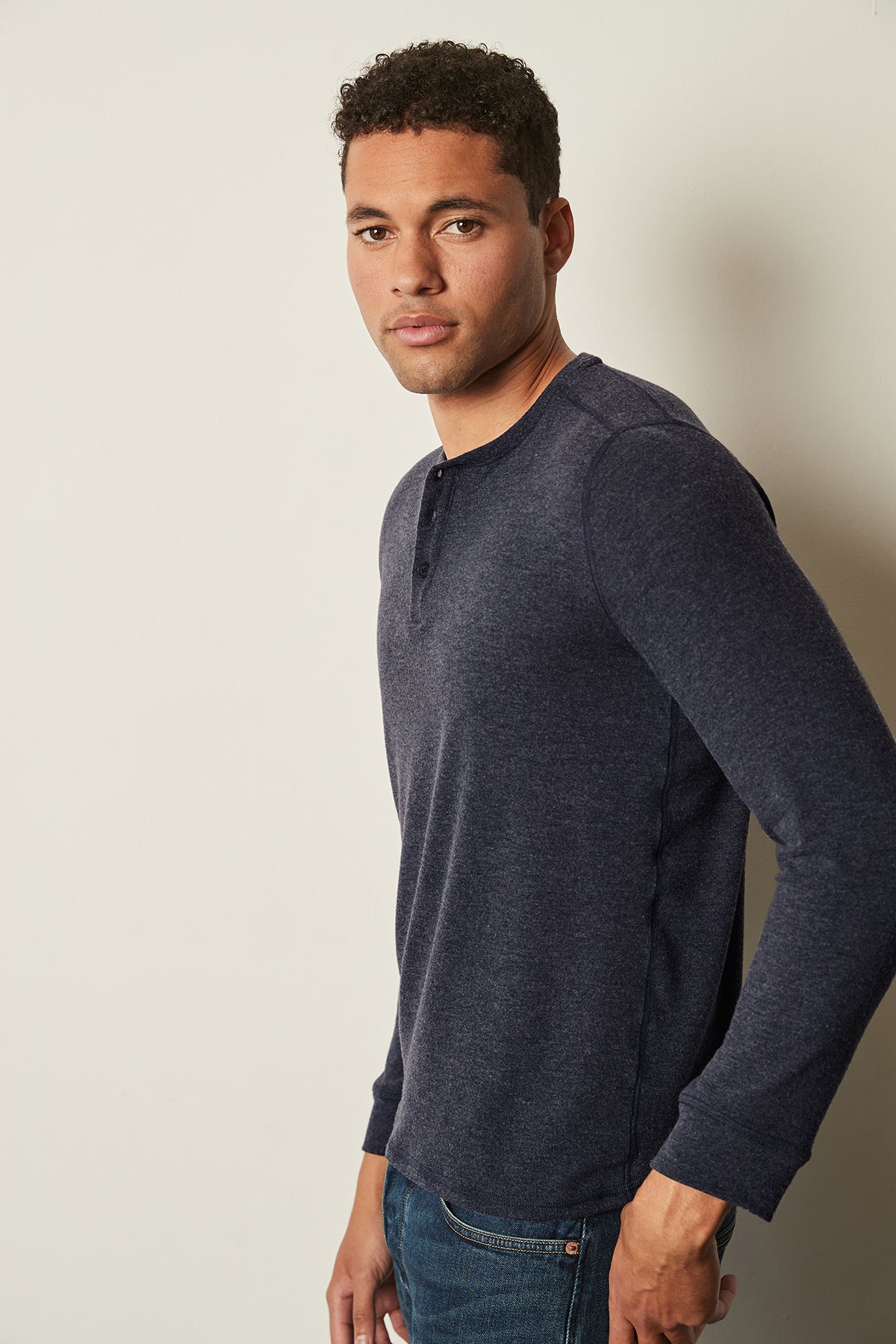 A versatile man in FAUST COZY JERSEY HENLEY by Velvet by Graham & Spencer jeans and a blue henley shirt, perfect for layering.-25484011733185