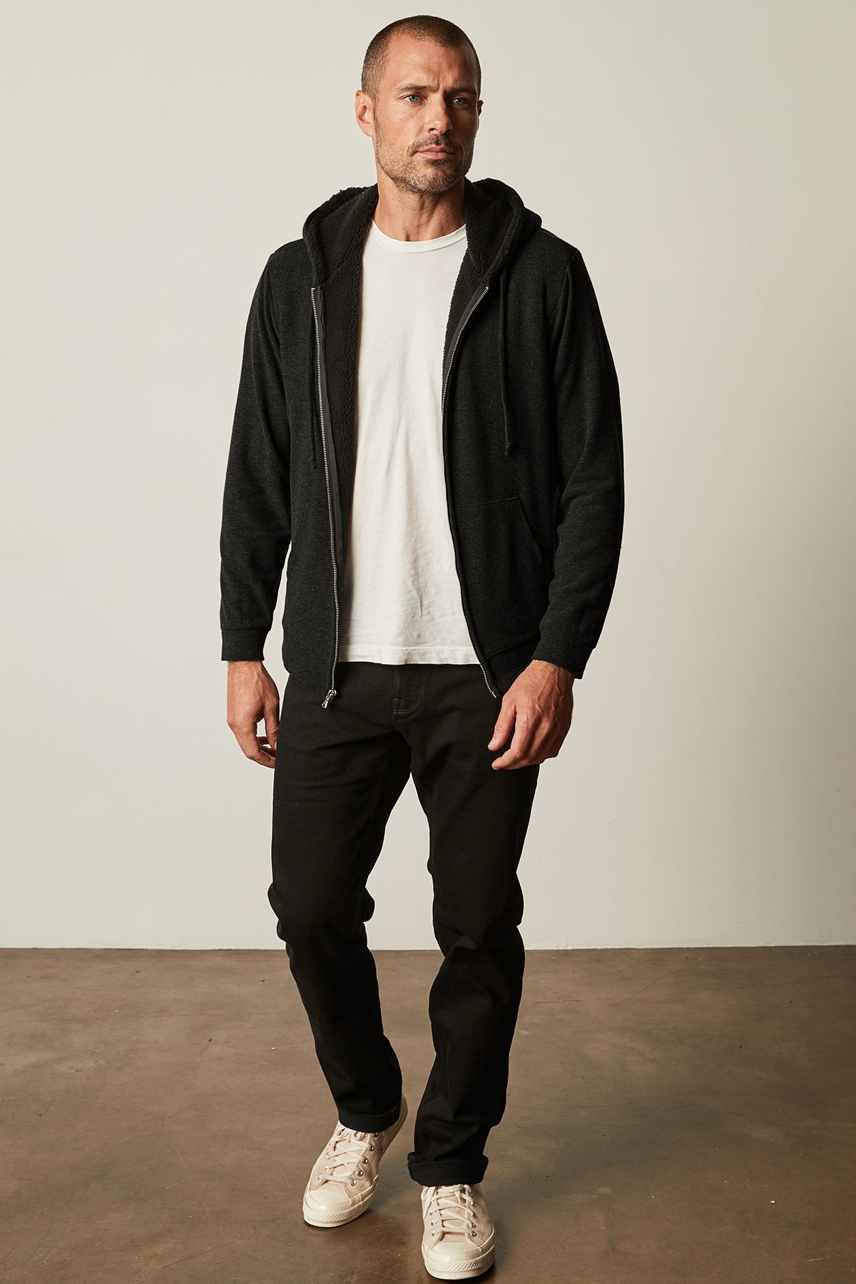 A man wearing a white SALVADORE SHERPA LINED HOODIE by Velvet by Graham & Spencer with an adjustable drawstring hood.-25484071272641