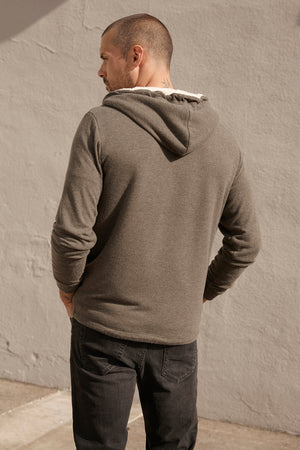 The back of a man wearing a Velvet by Graham & Spencer SALVADORE SHERPA LINED HOODIE with an adjustable drawstring hood and soft jersey fabric.