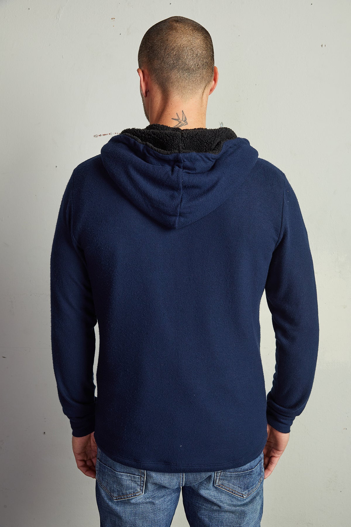   The back of a man wearing a Velvet by Graham & Spencer SALVADORE SHERPA LINED HOODIE with an adjustable drawstring hood and jeans. 