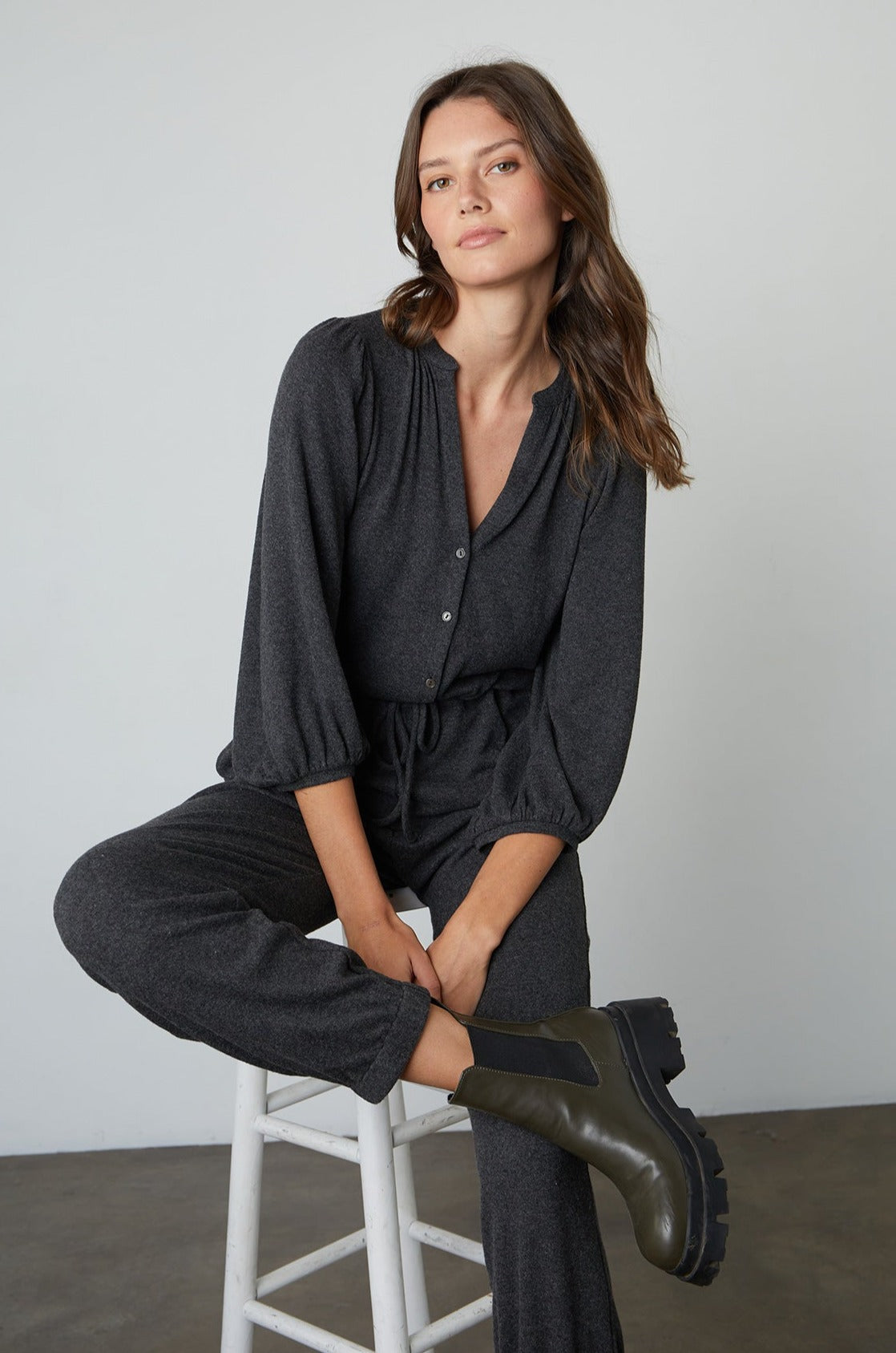   Model sitting on stool wearing Sariah Cozy Lux Romper in Anthracite Front 