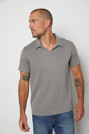 A man wearing a grey Velvet by Graham & Spencer DILAN COTTON BLEND POLO, a structured fit, and jeans.