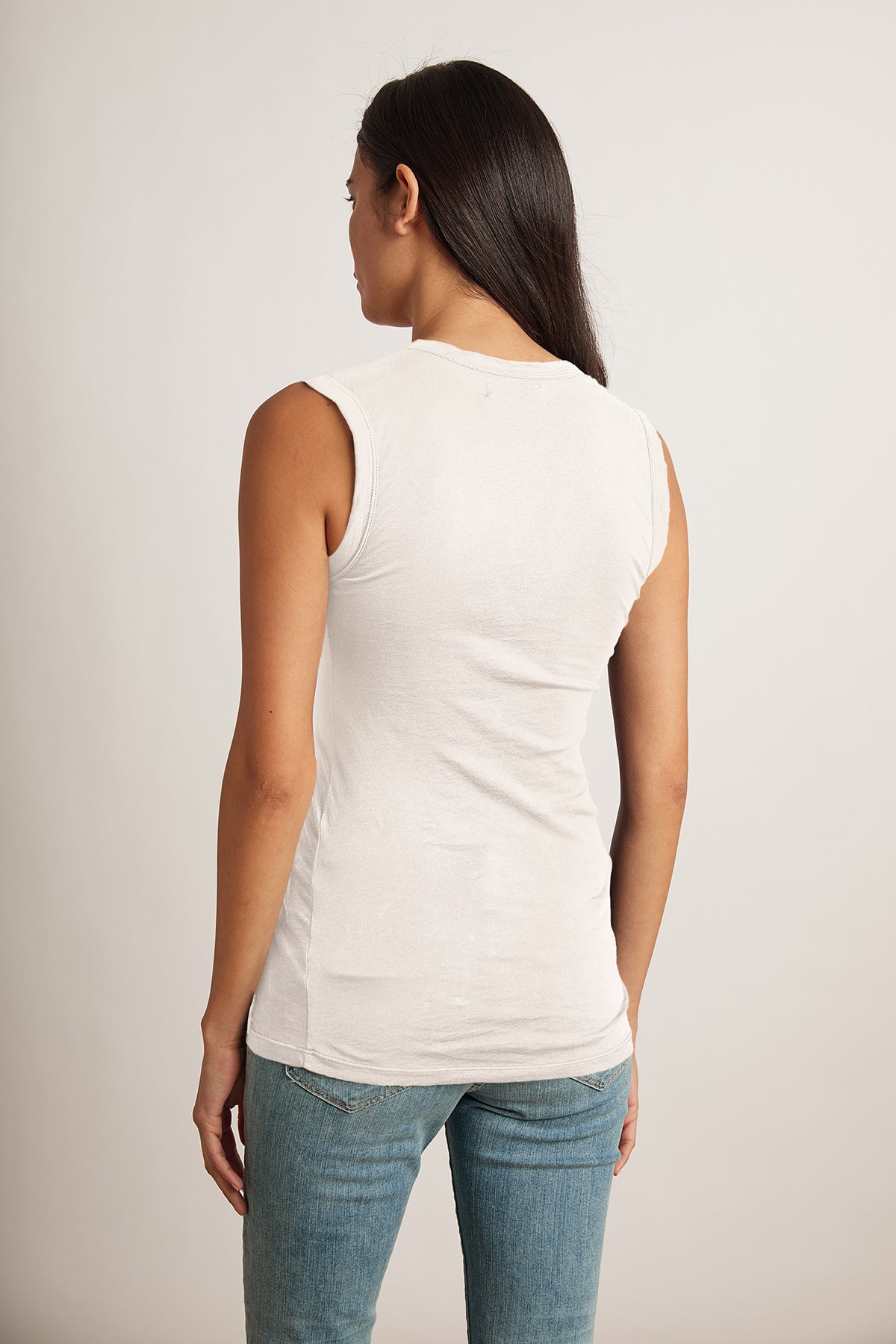   The back view of a woman wearing jeans and a Velvet by Graham & Spencer ESTINA GAUZY WHISPER FITTED TANK TOP. 