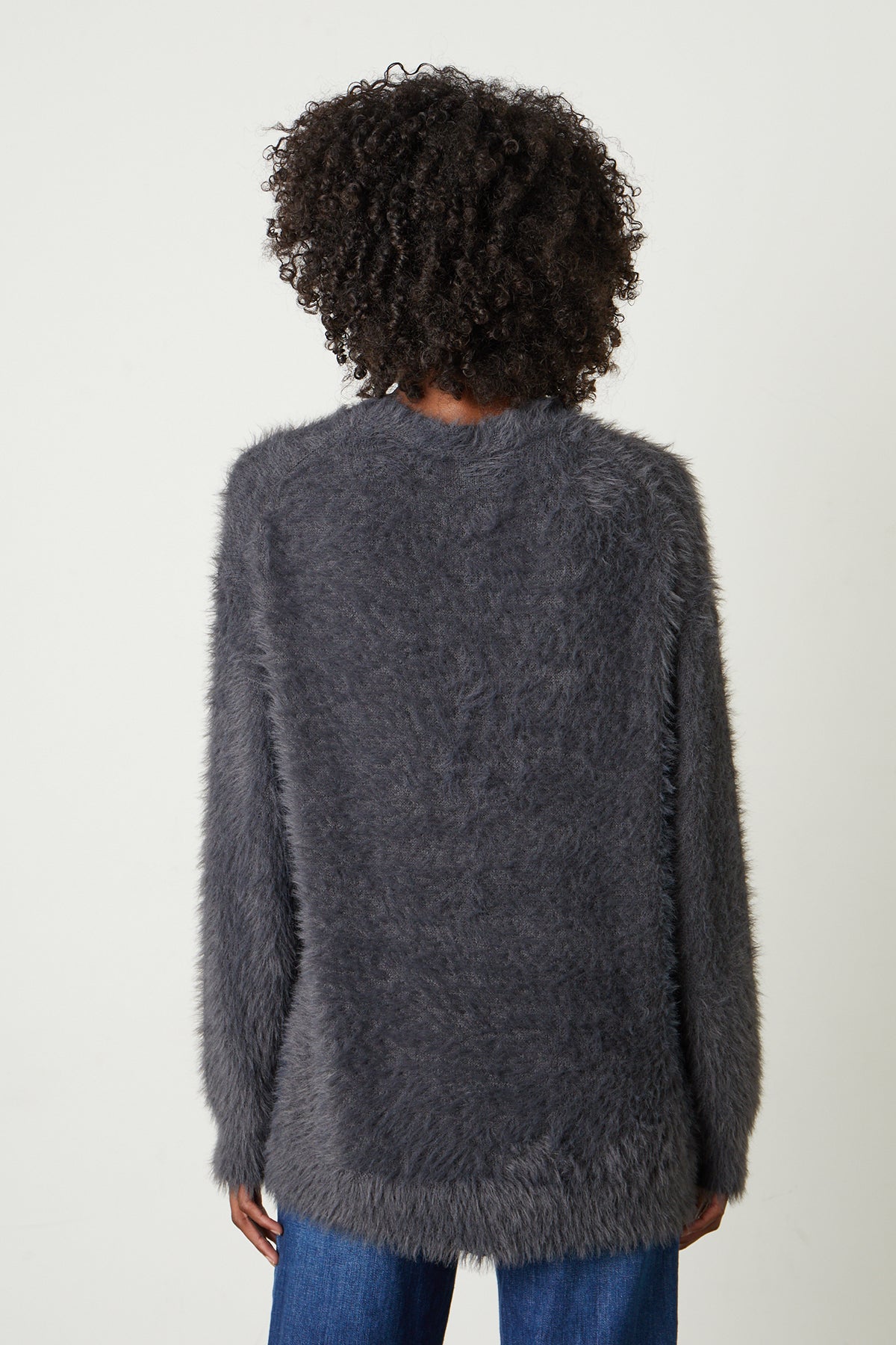 The back view of a woman wearing a Velvet by Graham & Spencer BARB FEATHER YARN BUTTON FRONT CARDIGAN.-25985017675969