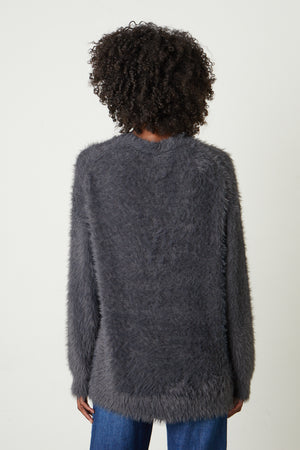 The back view of a woman wearing a Velvet by Graham & Spencer BARB FEATHER YARN BUTTON FRONT CARDIGAN.