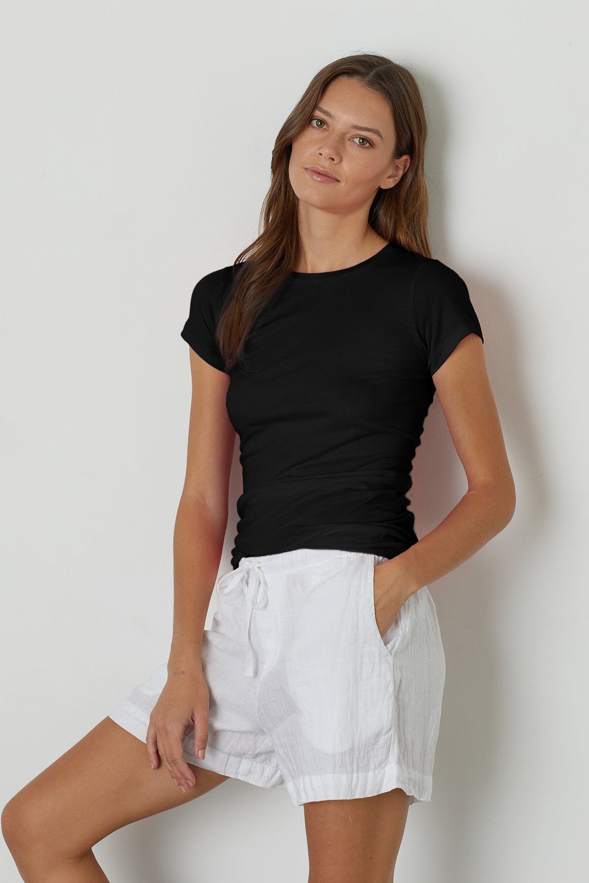 A woman wearing a black t-shirt and Velvet by Graham & Spencer's TAMMY DRAWSTRING LINEN SHORT with an elastic waist.-24937241149633