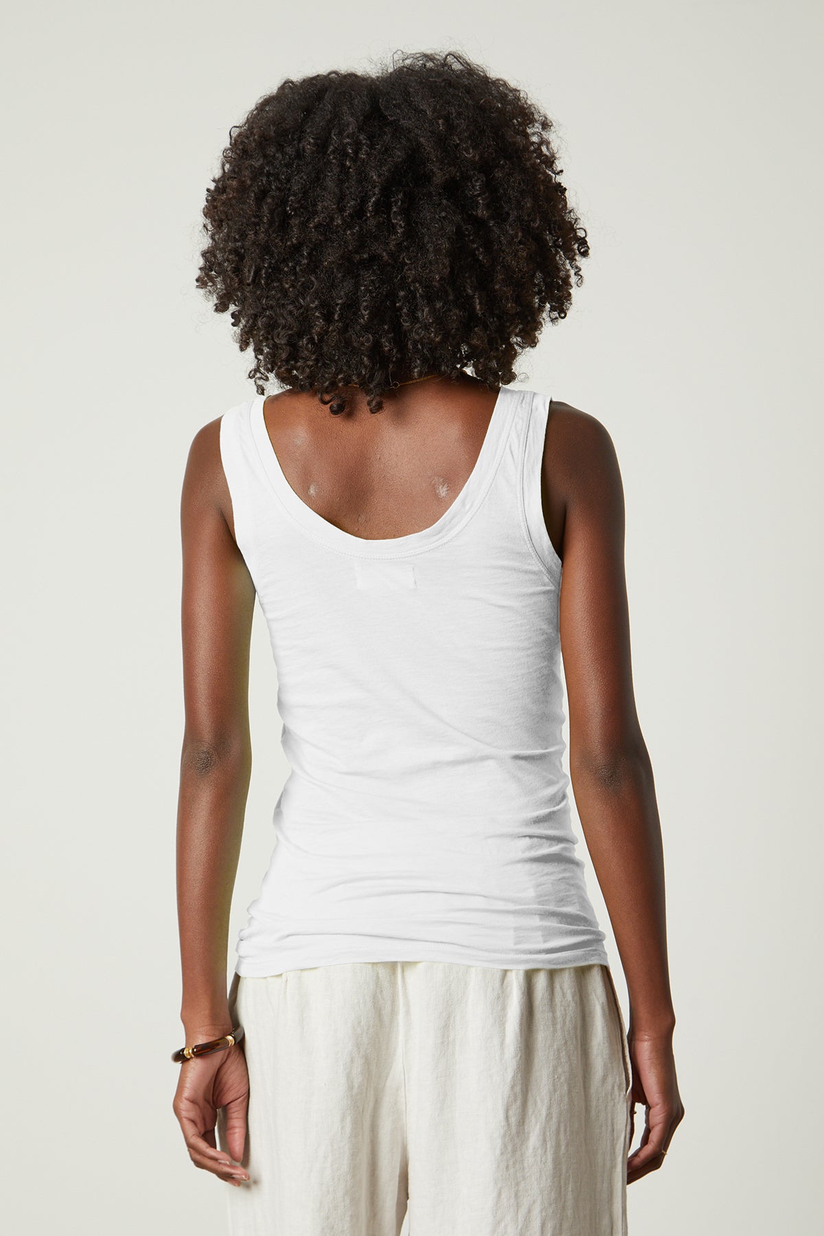 The back view of a woman wearing a Velvet by Graham & Spencer MOSSY GAUZY WHISPER FITTED TANK.-26087949140161