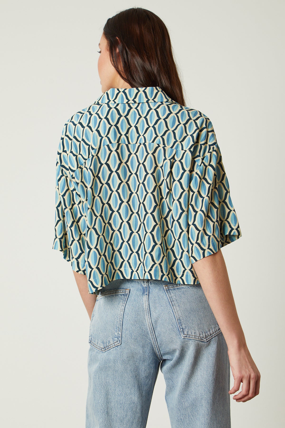 The back view of a woman wearing jeans and the Velvet by Graham & Spencer BECKETT PRINTED BUTTON-UP TOP with a geometric pattern and higher waist jean.-26078942527681