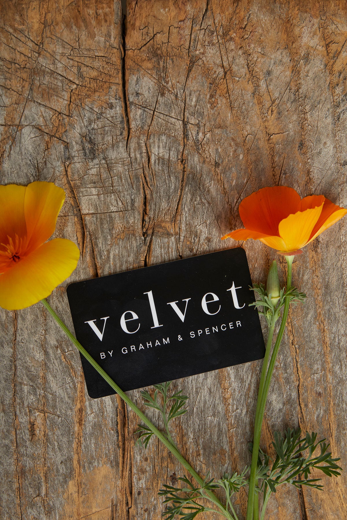   A Velvet by Graham & Spencer E-Gift Card sitting on a wooden table. 