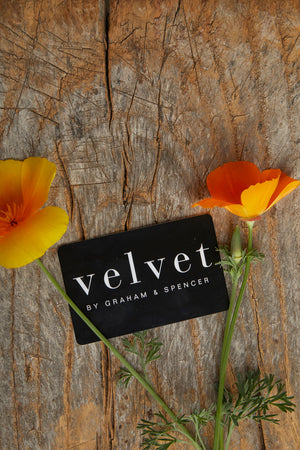 A Velvet by Graham & Spencer E-Gift Card sitting on a wooden table.