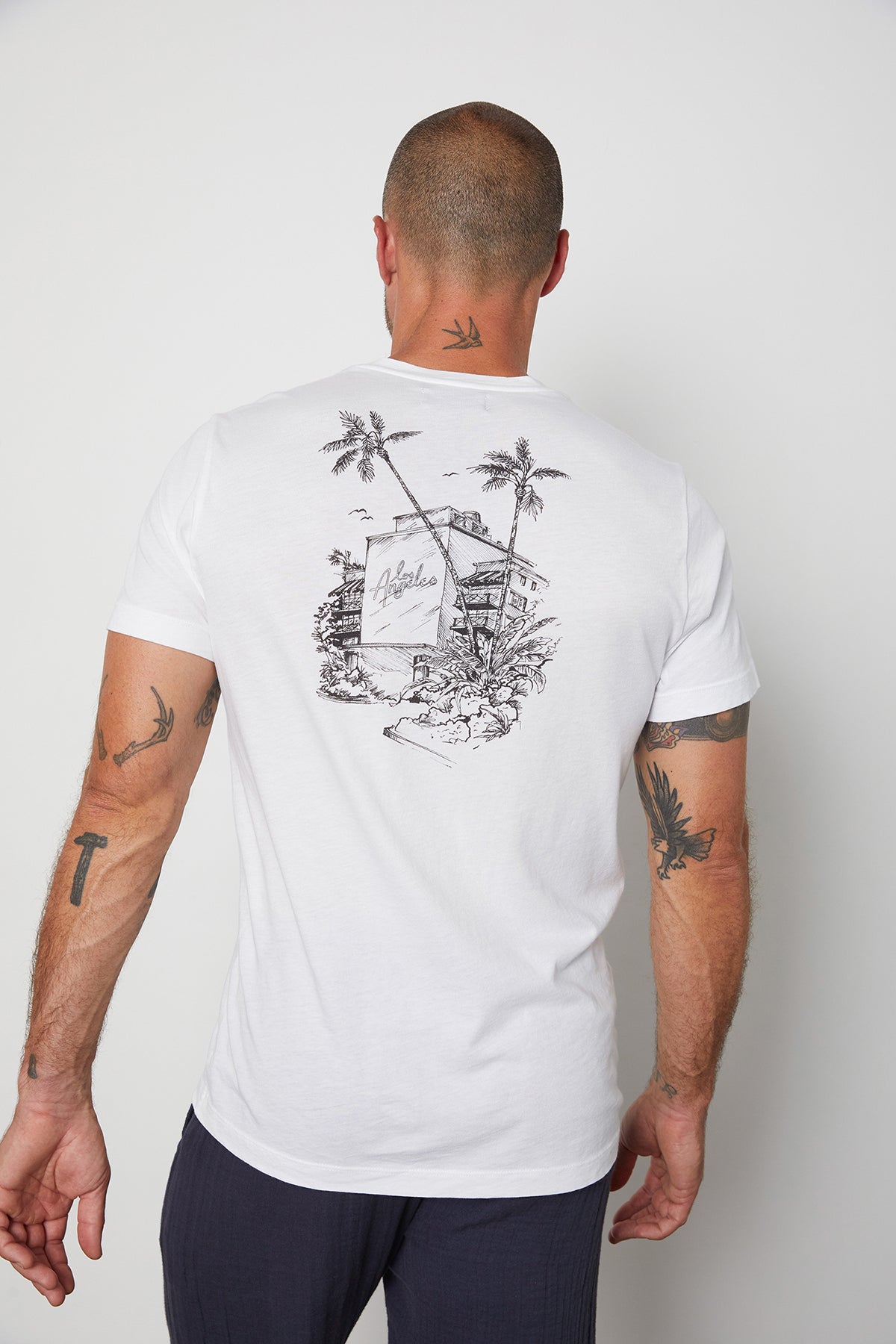 Back view of white Angelo crew neck tee with black sketch graphic on back representing Los Angeles with building and palm trees.-24605755015361