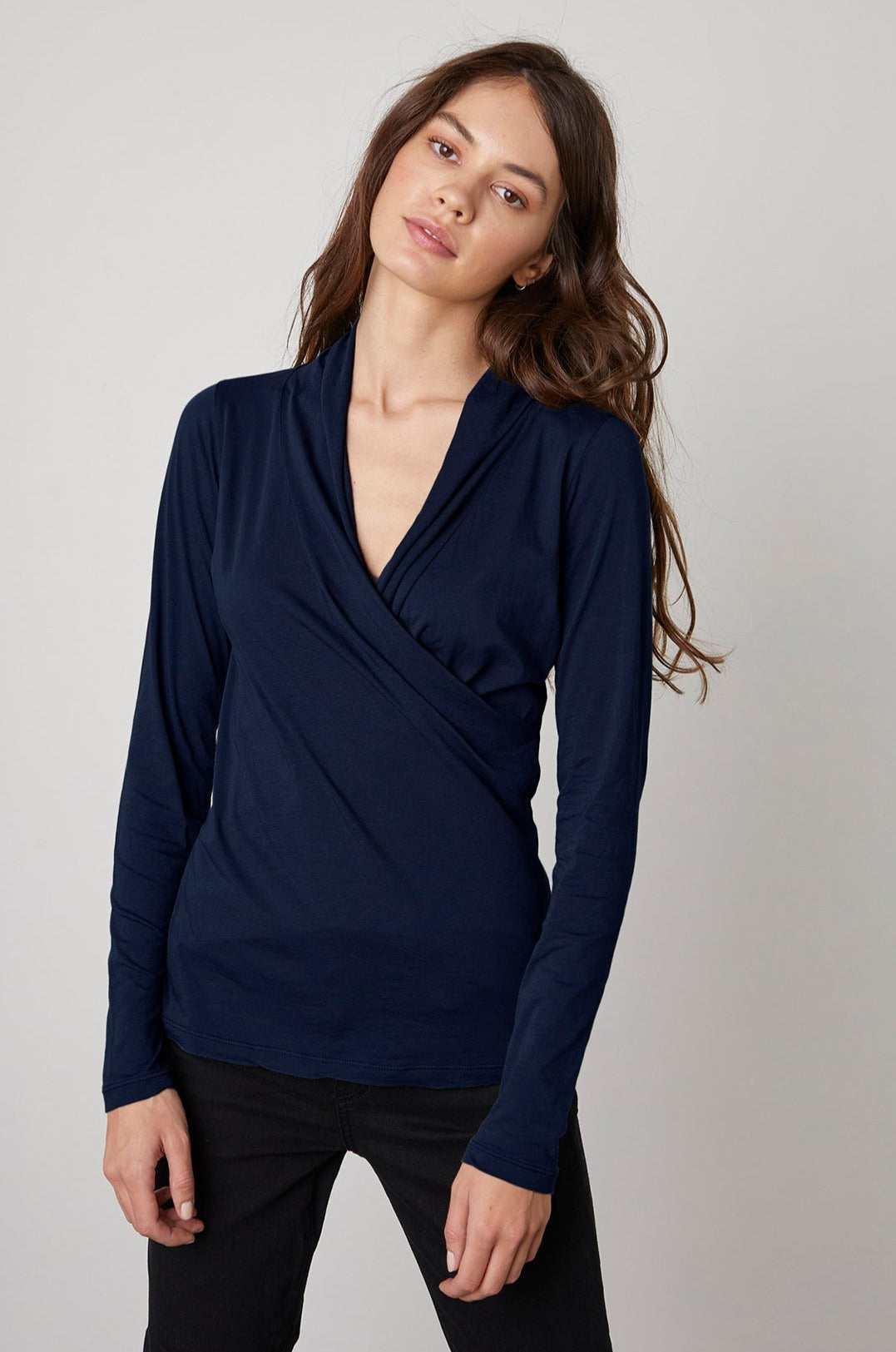 The model is wearing a Velvet by Graham & Spencer MERI WRAP FRONT FITTED TOP with a v - neck.-23013992792257