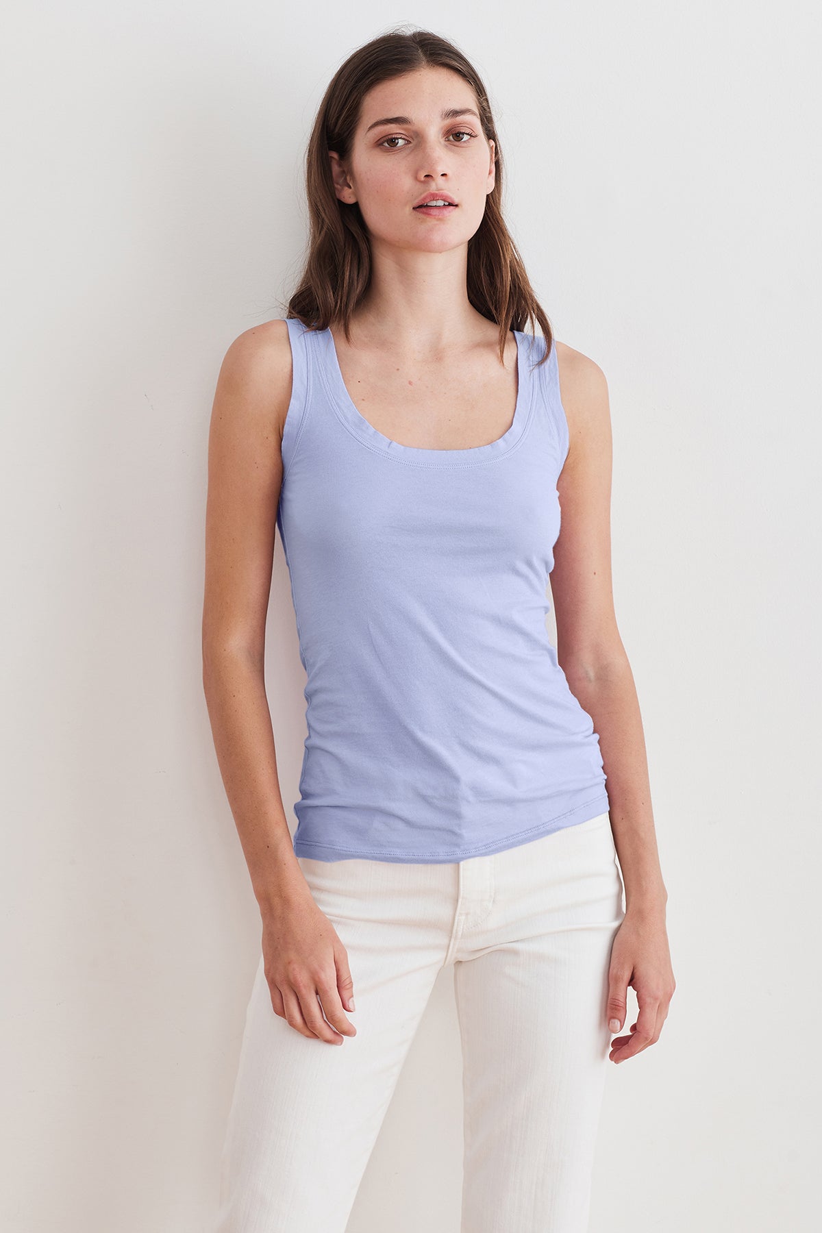 A woman wearing a Velvet by Graham & Spencer MOSSY GAUZY WHISPER FITTED TANK, complemented with white jeans.-23854475215041