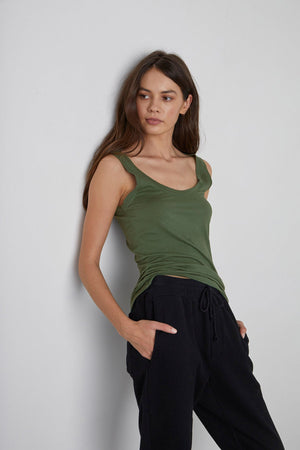 A woman wearing a Velvet by Graham & Spencer MOSSY GAUZY WHISPER FITTED TANK and black sweatpants, embracing back to basics style.