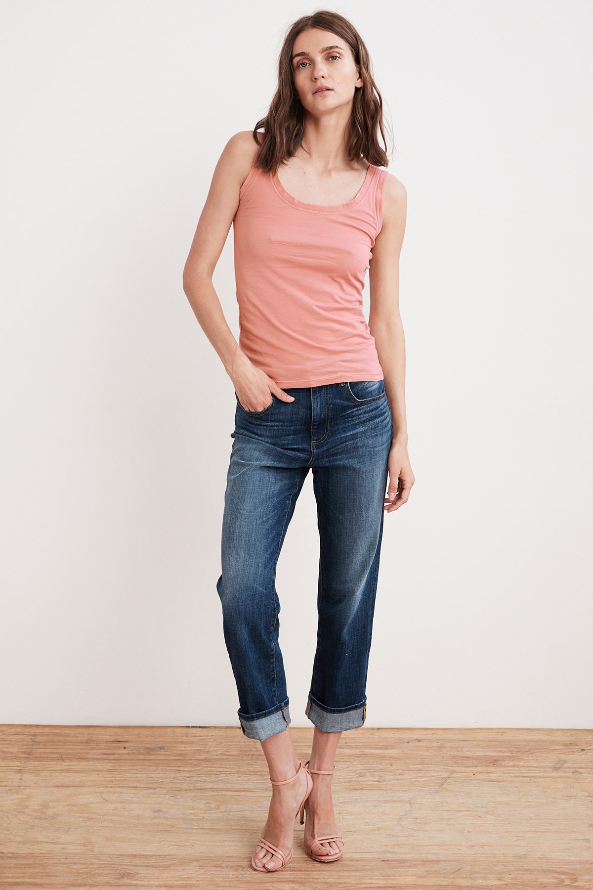   A woman wearing a MOSSY GAUZY WHISPER FITTED TANK in pink from Velvet by Graham & Spencer. Additionally, she is wearing jeans. 