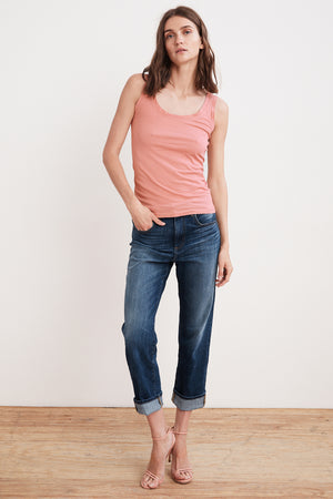 A woman wearing a MOSSY GAUZY WHISPER FITTED TANK in pink from Velvet by Graham & Spencer. Additionally, she is wearing jeans.