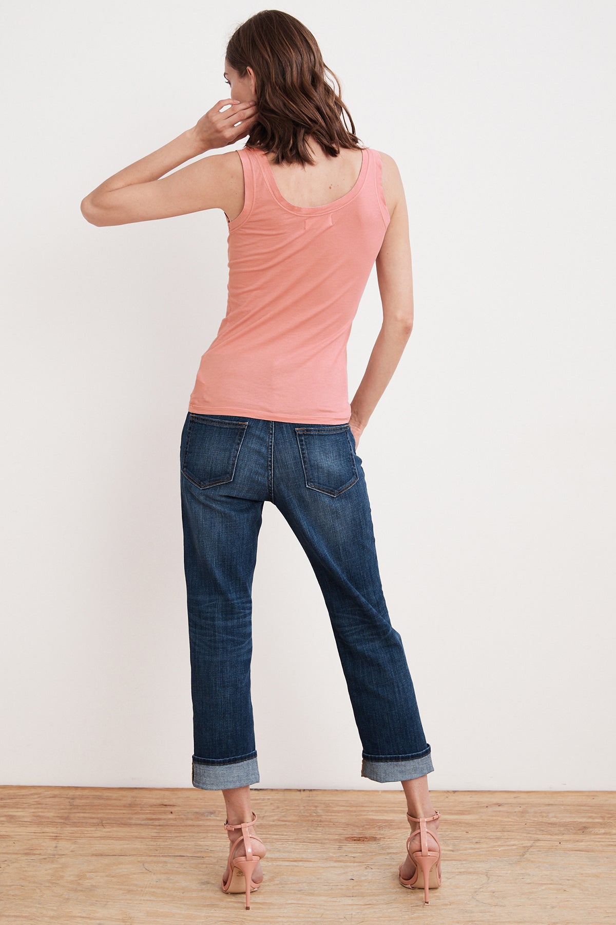   A woman wearing a MOSSY GAUZY WHISPER FITTED TANK in pink, perfect for warmer days paired with jeans for a trendy layering look by Velvet by Graham & Spencer. 