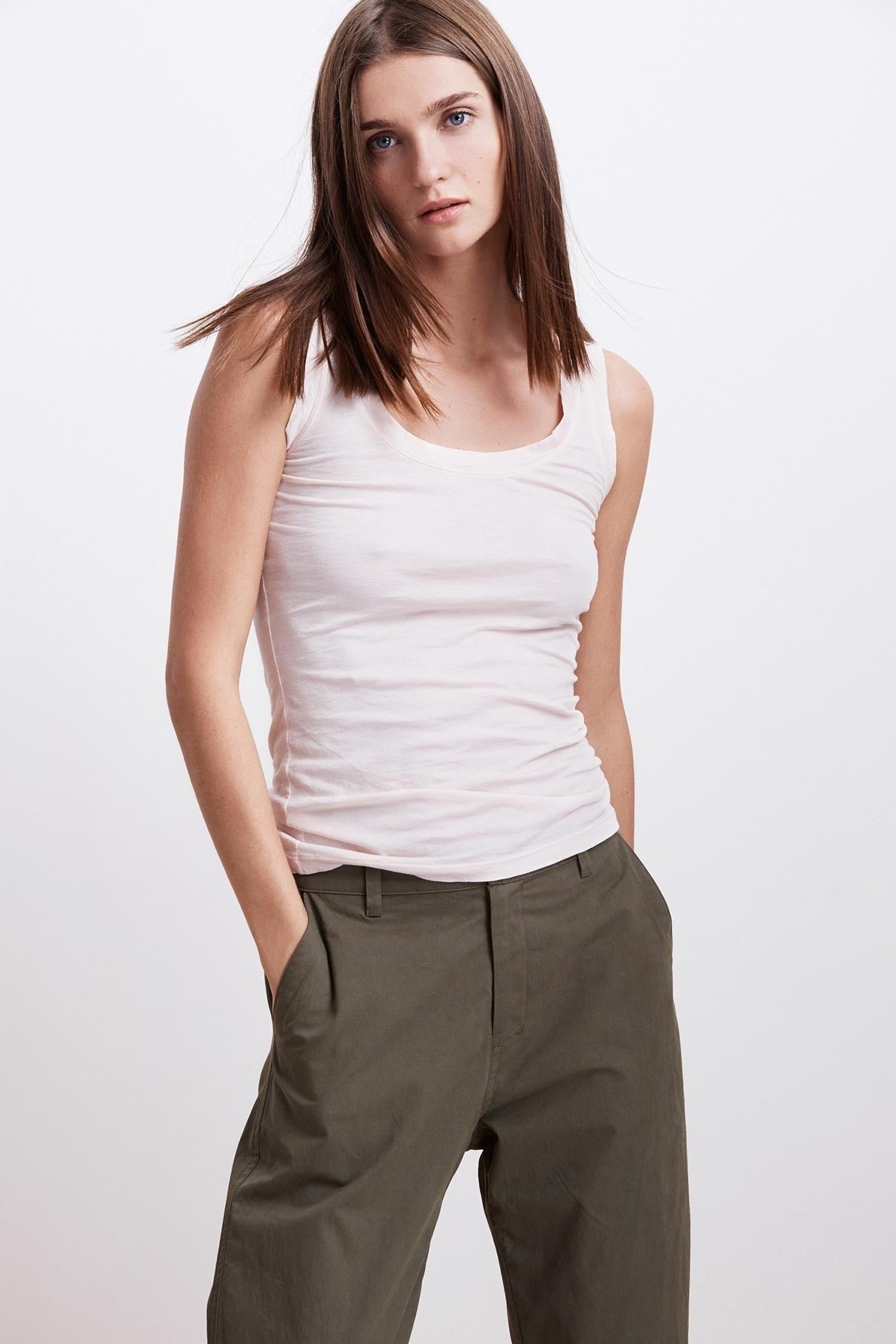  A woman in a pink MOSSY GAUZY WHISPER FITTED TANK, layered with an olive green pants. Brand: Velvet by Graham & Spencer. 