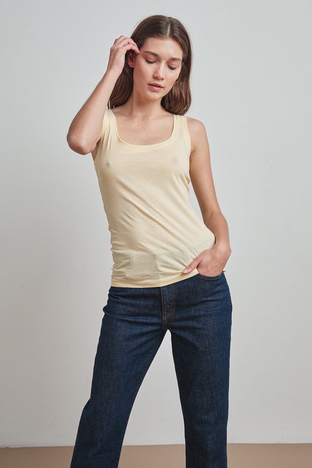   A woman wearing a MOSSY GAUZY WHISPER FITTED TANK in yellow by Velvet by Graham & Spencer for warmer days. 