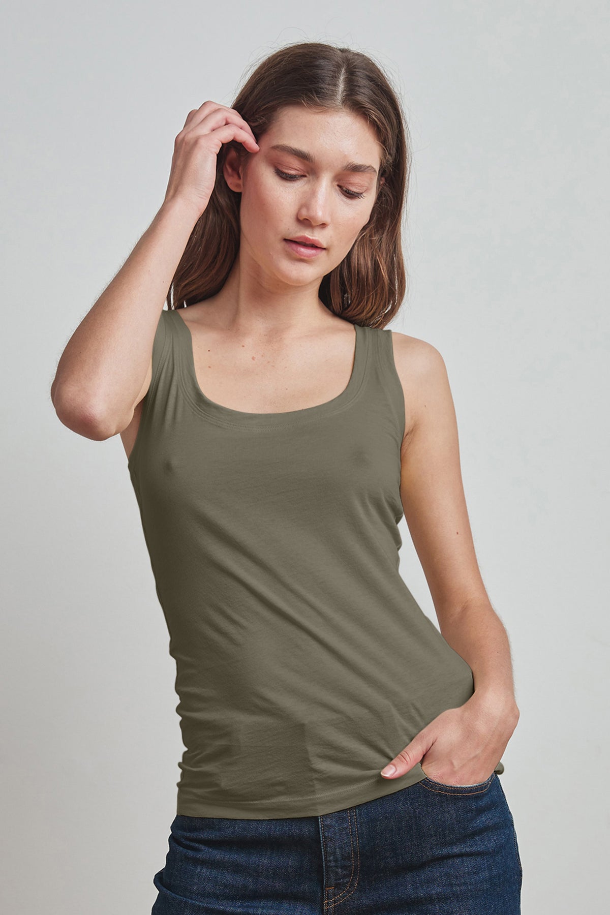   A woman wearing a Velvet by Graham & Spencer MOSSY GAUZY WHISPER FITTED TANK in olive green, perfect for warmer days and layering. 