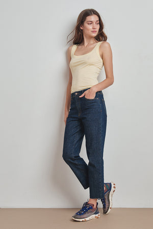 A woman embracing warmer days in a MOSSY GAUZY WHISPER FITTED TANK by Velvet by Graham & Spencer layered with jeans.