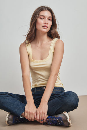 A woman sitting on the floor in a MOSSY GAUZY WHISPER FITTED TANK by Velvet by Graham & Spencer.