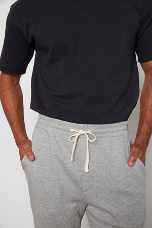 A man wearing a Velvet by Graham & Spencer JUDAS SWEATPANT with an elastic waist.
