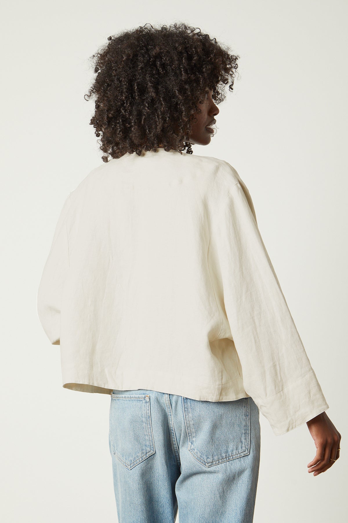 The back view of a woman wearing BRIELLE HEAVY LINEN JACKET by Velvet by Graham & Spencer jeans and a white jacket.-26215483113665