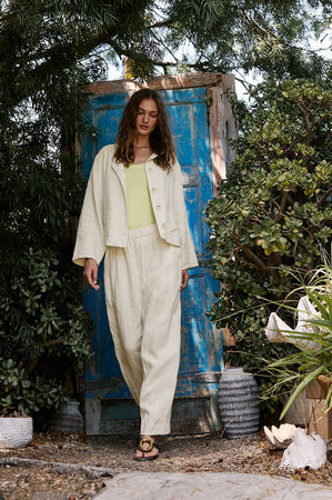 A woman is standing in front of the Velvet by Graham & Spencer BRIELLE HEAVY LINEN JACKET.