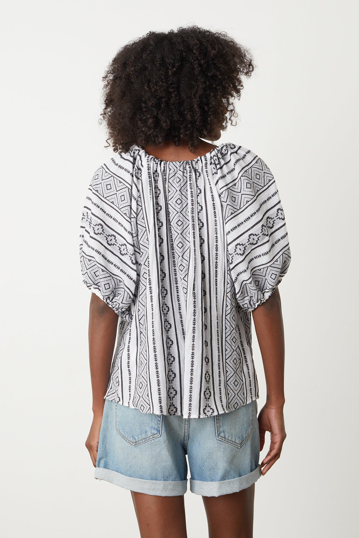A woman wearing the Velvet by Graham & Spencer KIMMY JACQUARD BOHO TOP in white with a black and white pattern.-26296063885505