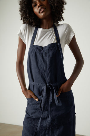 A woman wearing a durable LINEN APRON from Jenny Graham Home with an adjustable neck strap.