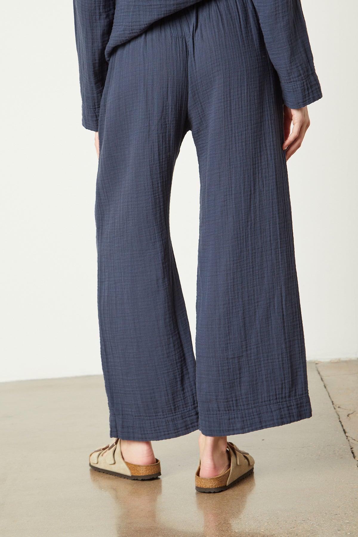   The back view of a woman wearing a blue wide leg PAJAMA PANT by Jenny Graham Home. 