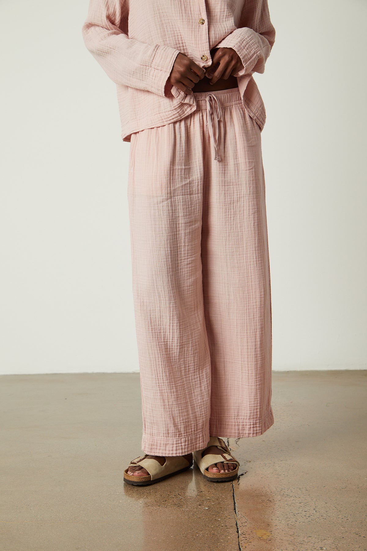   a woman wearing Jenny Graham Home pink linen pajama pants and sandals. 