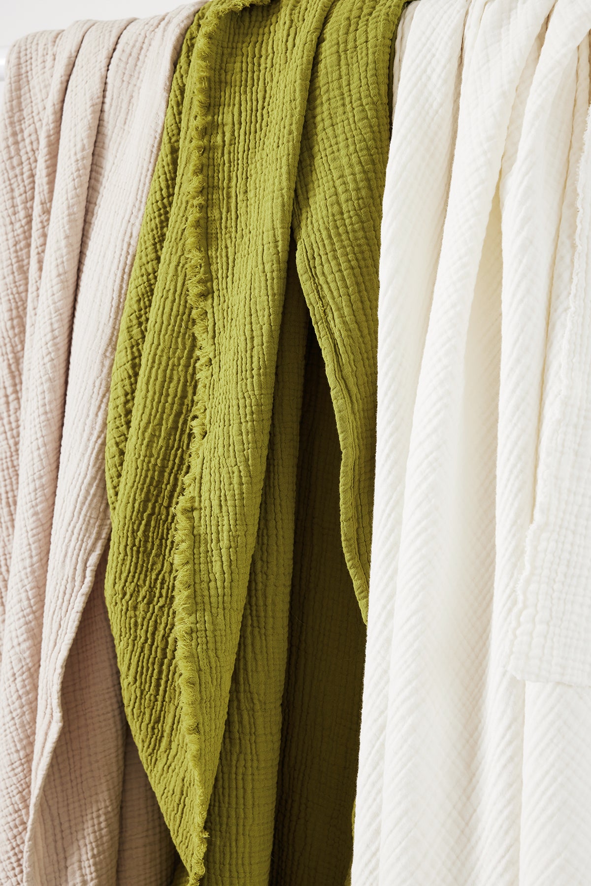 a white, green, and beige Cotton Gauze Throw hanging on a rack by Jenny Graham Home.-25519590604993