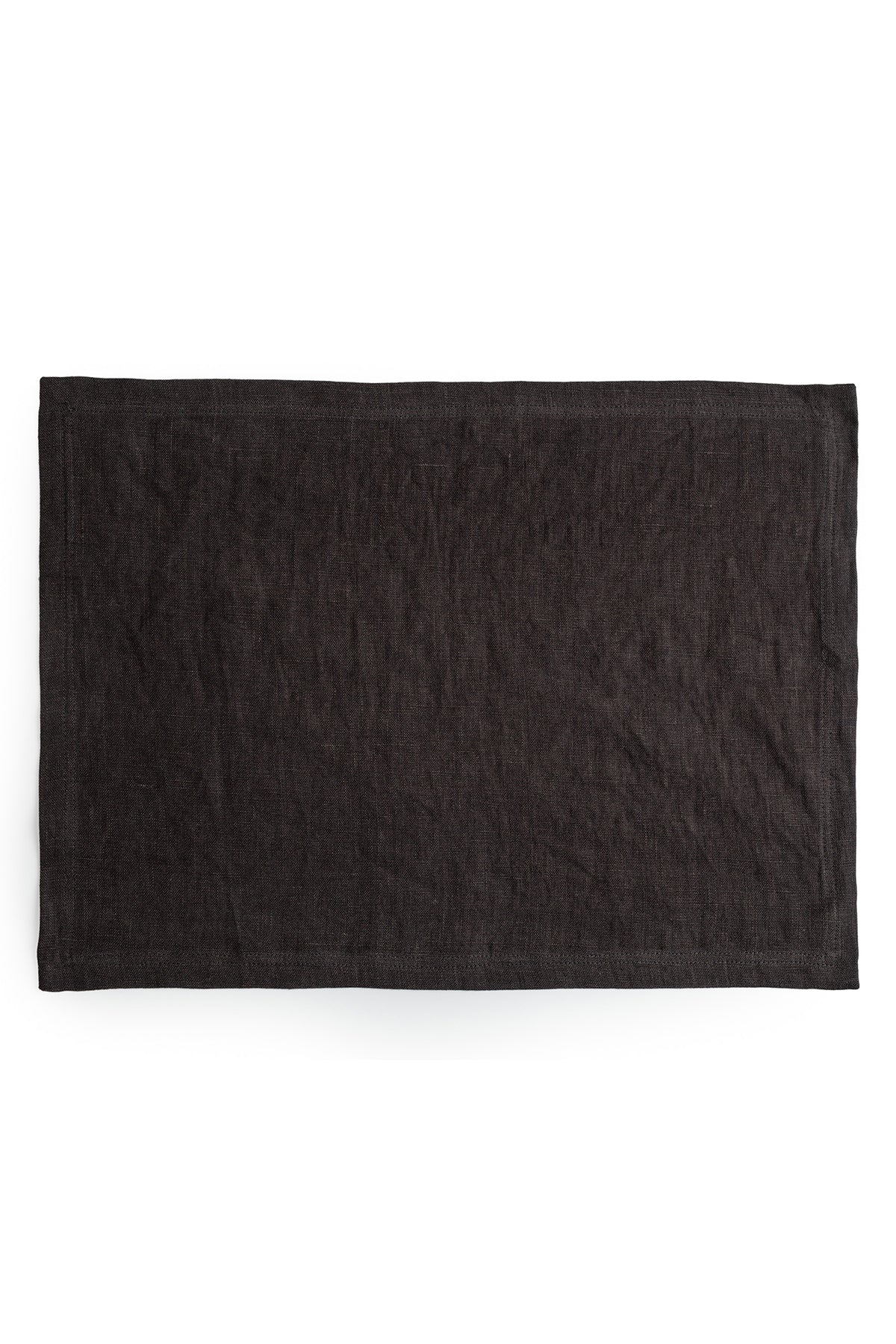 A plain black dyed linen placemat from Jenny Graham Home placed flat on a white background.-15072810467521